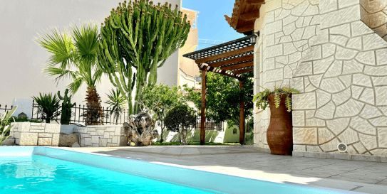 Traditional Greek-style Villa Olia with a lush garden, perfect for a relaxing short-term rental experience.
